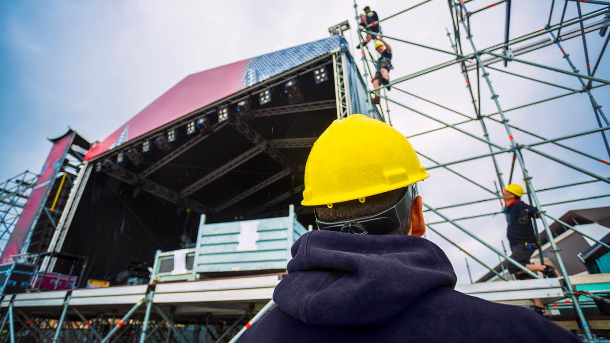 team building up the music stage for a festival, with personal protective equipment